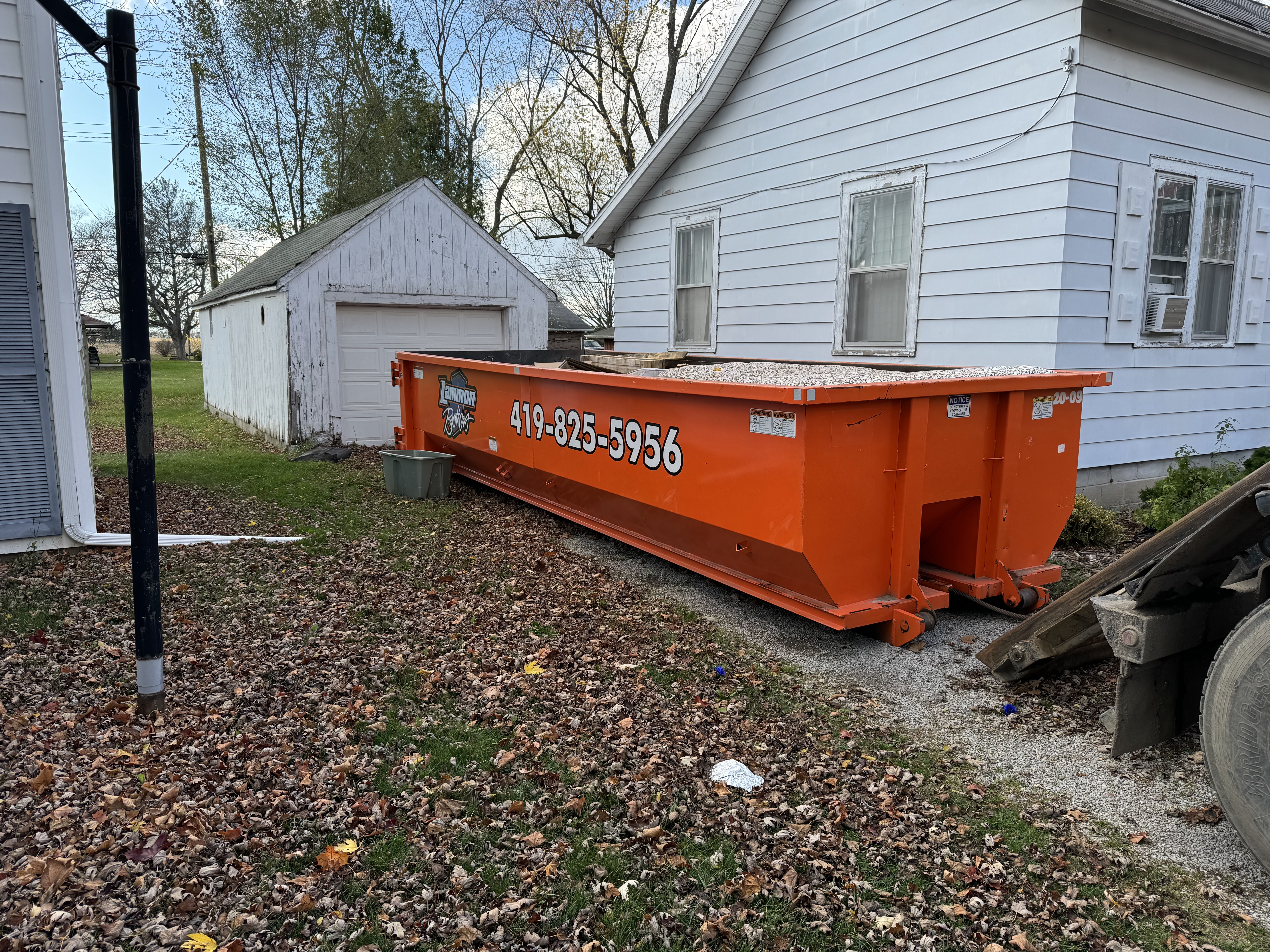 Orange Lammon Bros roll-off dumpster being set down at a Holland home