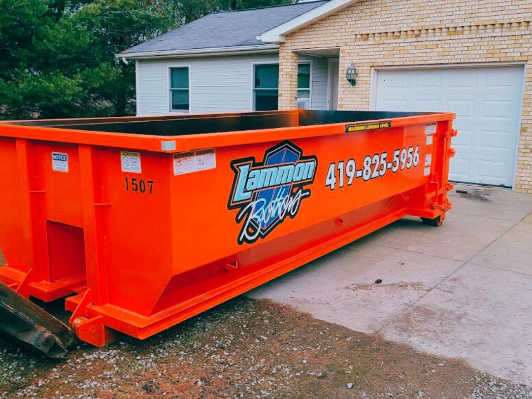Orange branded Lammon Bros roll-off dumpster on a residential driveway