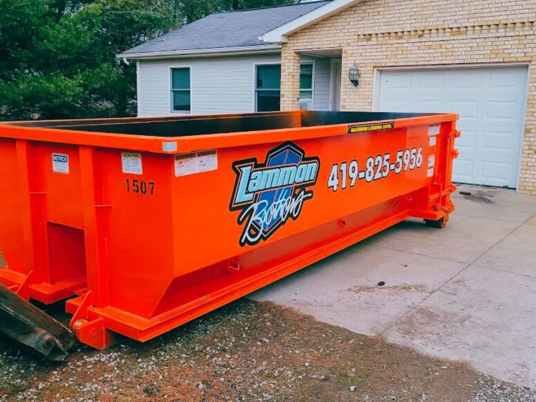 Orange branded Lammon Bros roll-off dumpster on a residential driveway