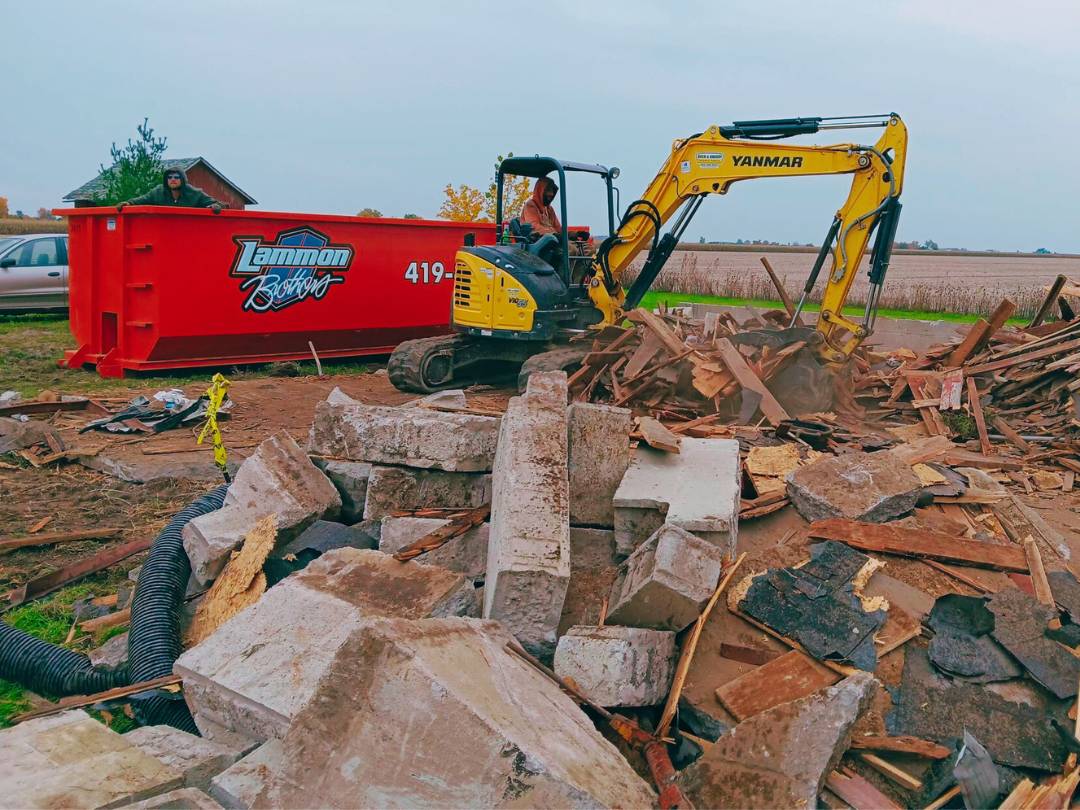 Lammon Bros dumpster on a demolition jobsite with an excavator loading debris