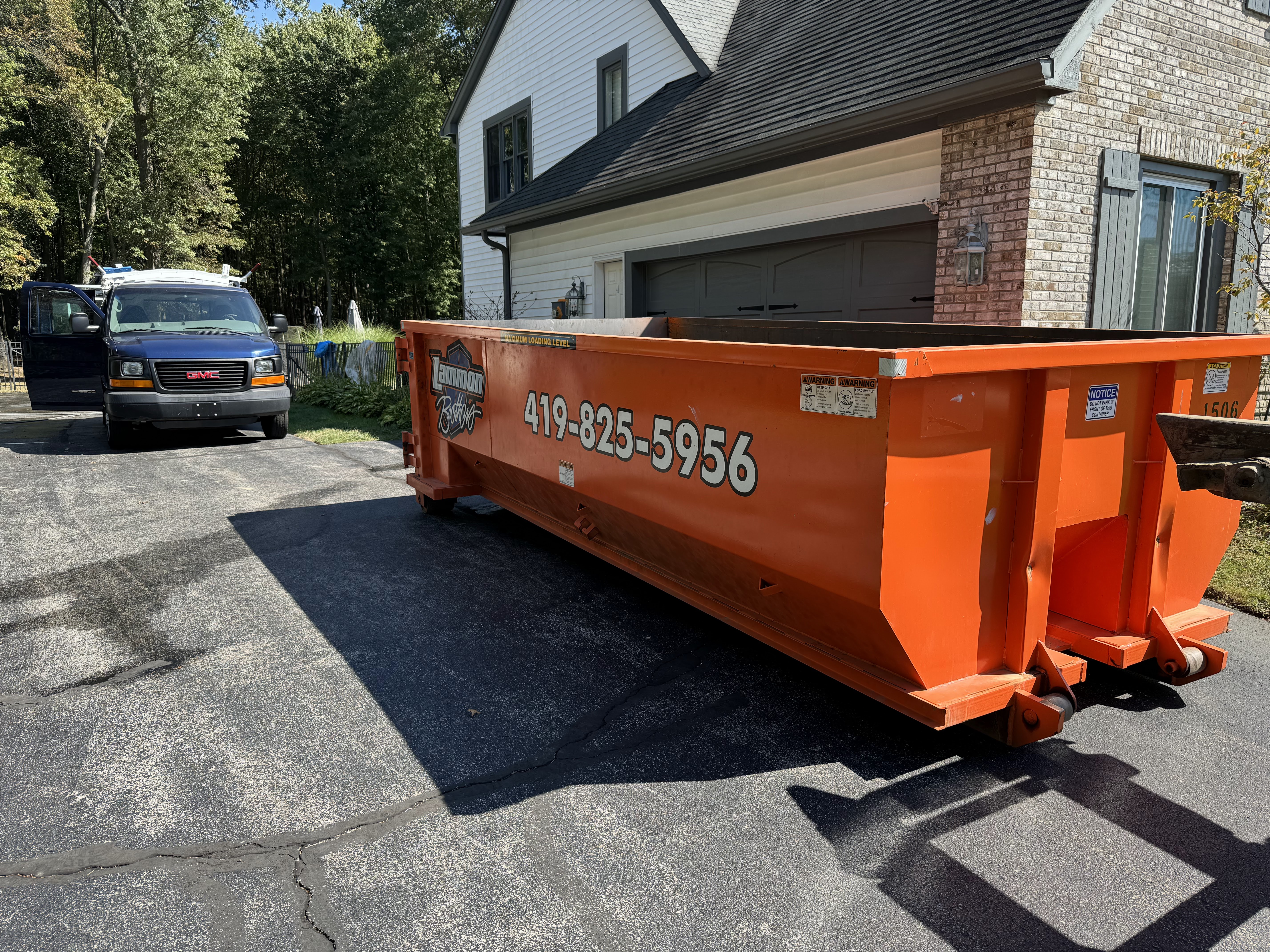 Orange Lammon Bros roll-off dumpster on a driveway