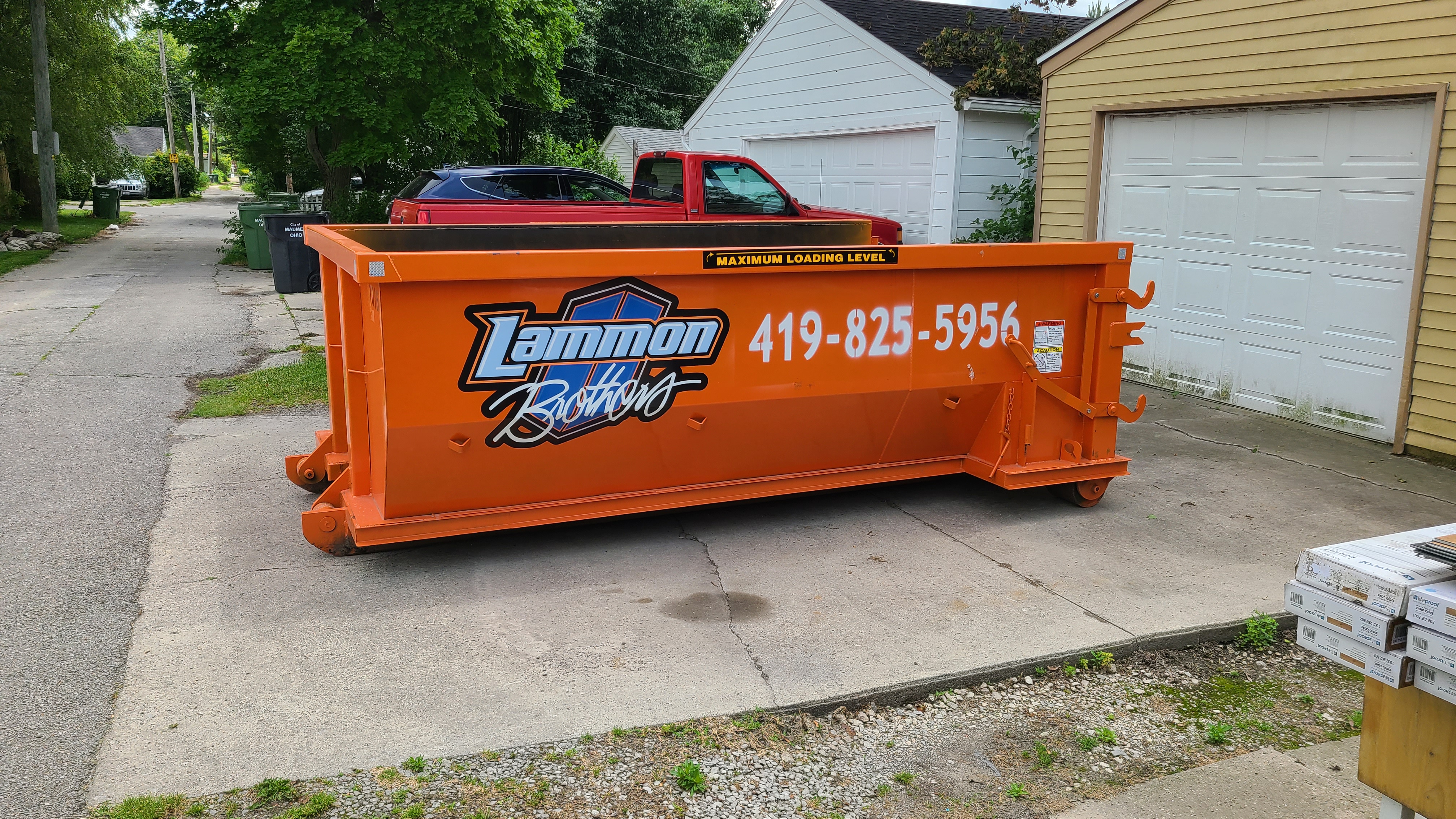 Orange Lammon Bros roll-off dumpster on a residential driveway