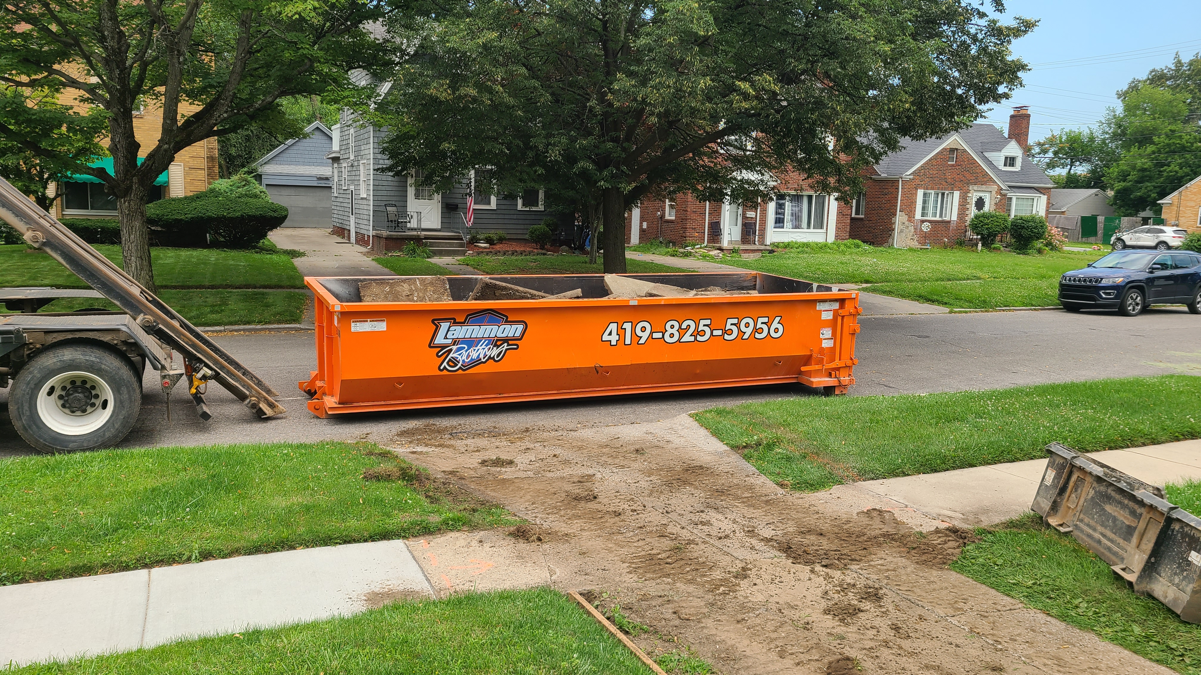Orange Lammon Bros roll-off dumpster sitting on a residential lawn