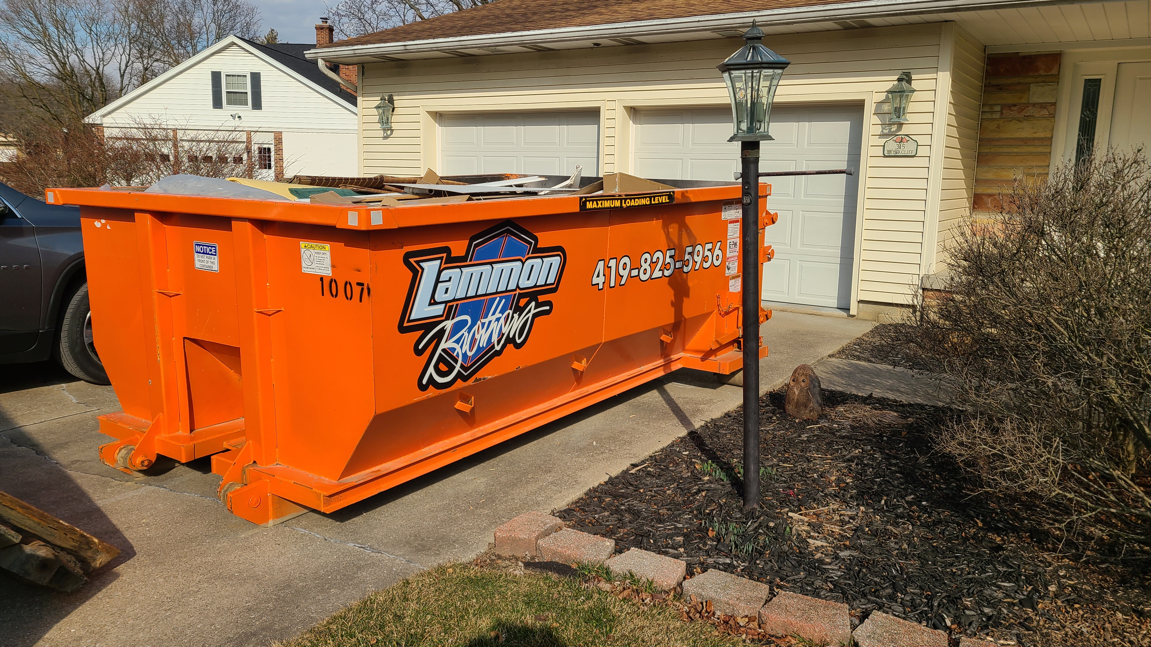 Orange Lammon Bros roll-off dumpster partly loaded with construction debris