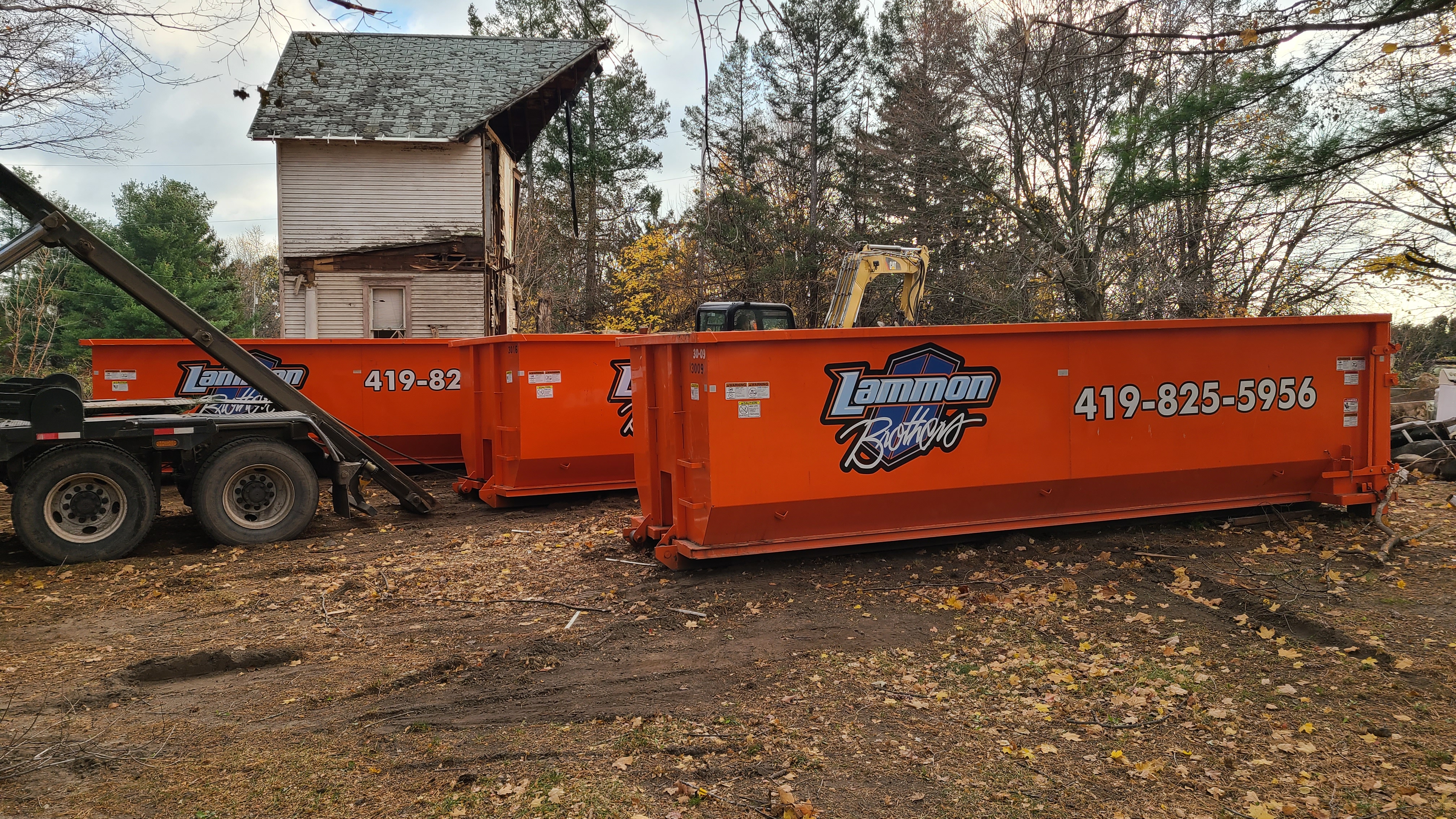 Two orange Lammon Bros roll-off dumpsters lined up at a Delta job site