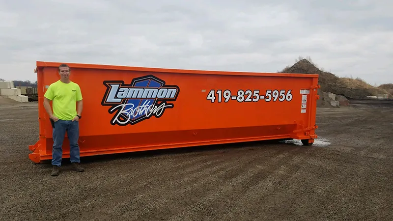 Jim from Lammon Bros standing alongside an orange 30-yard roll-off dumpster for scale at our Delta yard