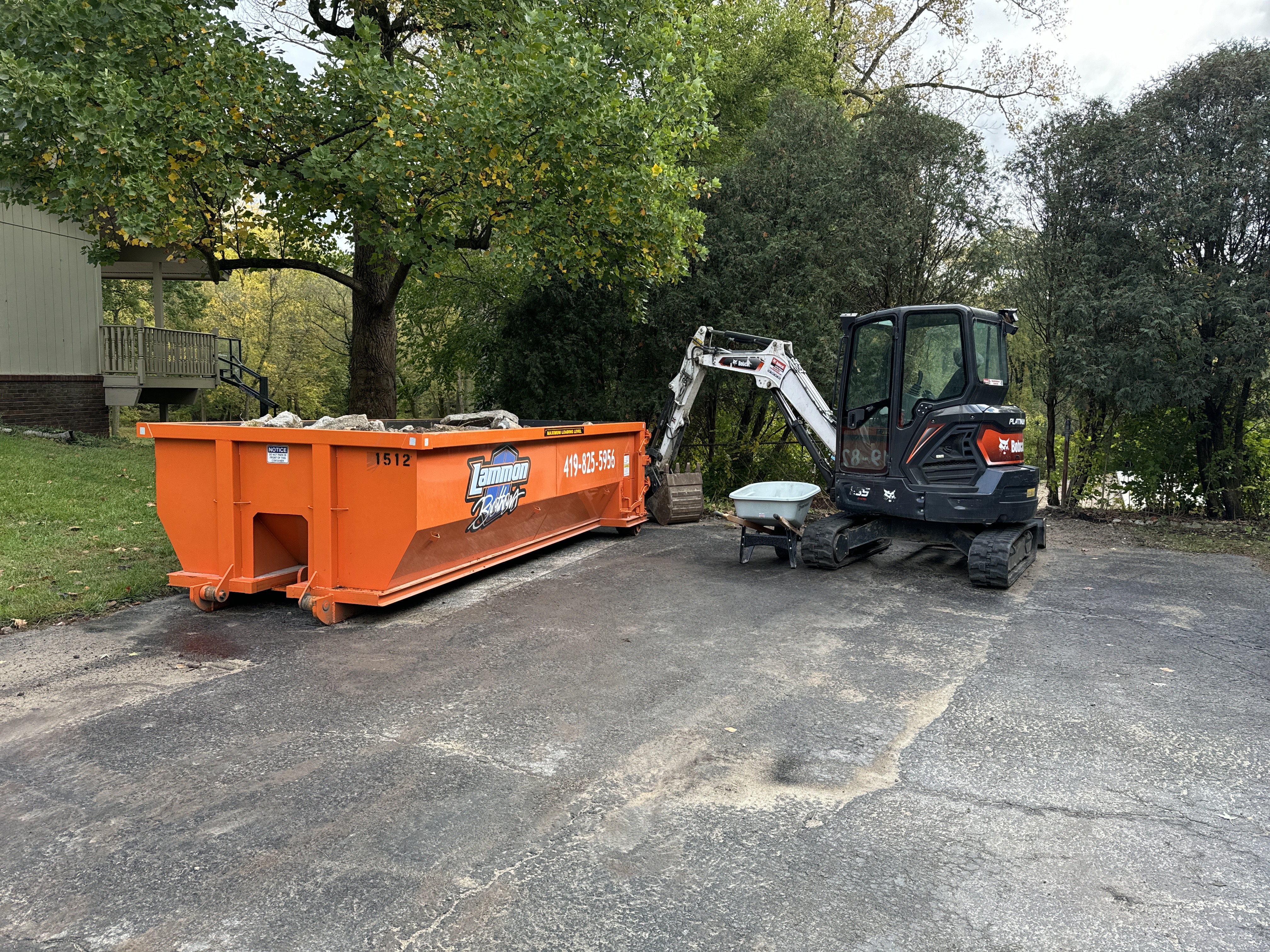 Orange Bobcat compact loader next to a Lammon Bros dumpster