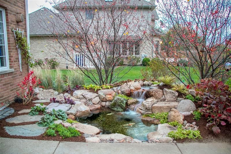 Finished landscape bed with decorative rock and a water feature, built with Lammon Bros materials
