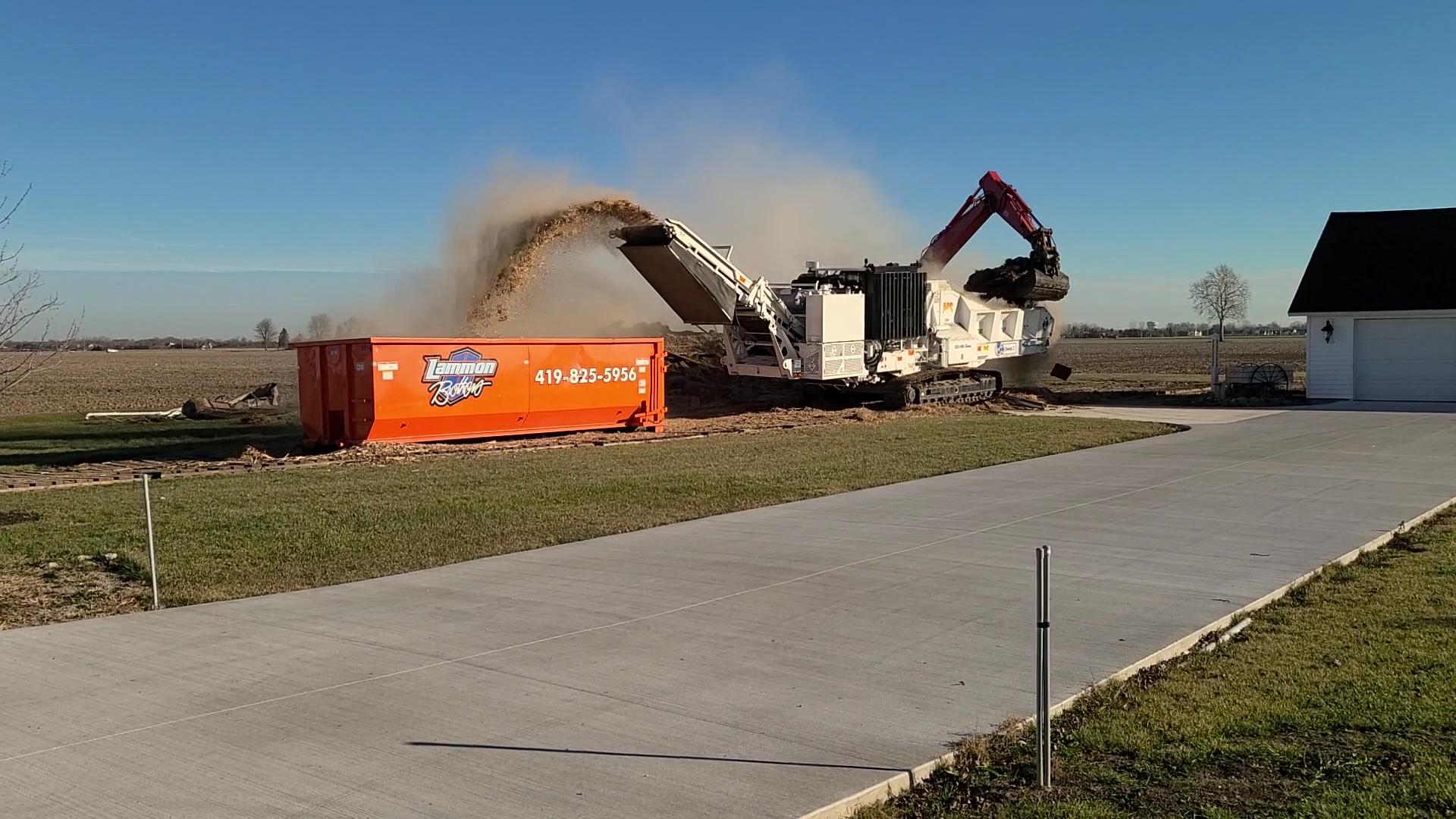 Tub grinder blowing ground wood into a mulch pile at the Lammon Bros yard