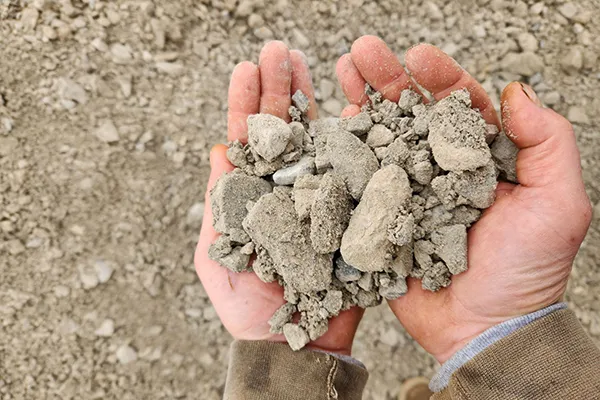 Hands holding whitish-gray #304 crushed limestone