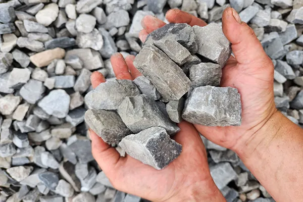 Hands holding large angular #4 limestone chunks