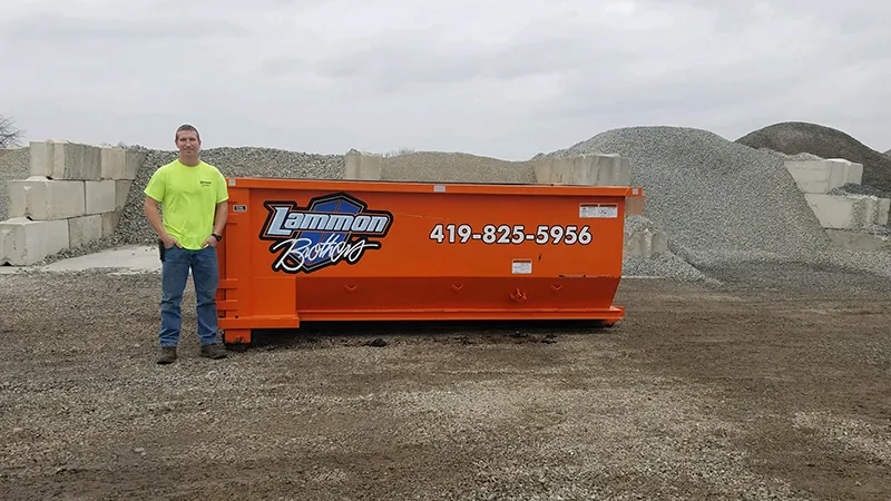 Orange 10-yard dumpster for rent in Toledo, Ohio, positioned in a store yard. A man stands adjacent to the dumpster to visually display its size and capacity. Ideal for small to medium home renovation or construction projects.